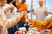 Mixed race family hands crossed other during prayer before holiday dinner