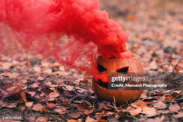 pumpkin with red smoke in the forest - scary pumpkin faces stock pictures, royalty-free photos & images