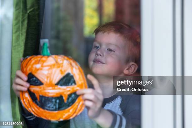 young boy sticking his pumpkin drawing on home window - sticky stock pictures, royalty-free photos & images