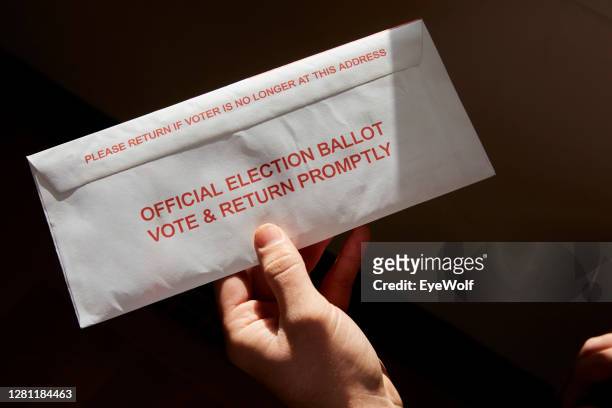 a person standing inside his home holding his mail in voting ballot - voting by mail stock pictures, royalty-free photos & images
