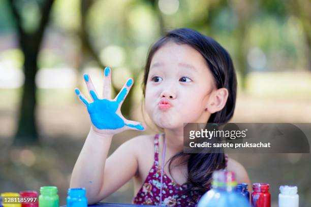 happy little child painting water color with her hand. smiley little child girl with painted hand. - human body part stock pictures, royalty-free photos & images