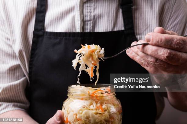 a man in an apron holding a fermented cabbage. - sauerkraut stock pictures, royalty-free photos & images