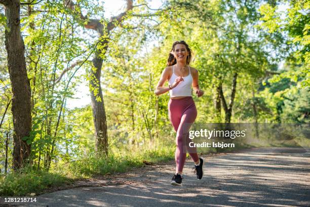 junge sportliche frau joggt durch den wald. - joggerin park stock-fotos und bilder