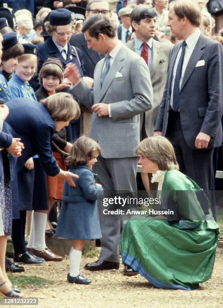 Lady Diana Spencer, wearing a green dress with a pie crust frill collar, kneels down to greet a child during a visit to Broadlands, the former home...