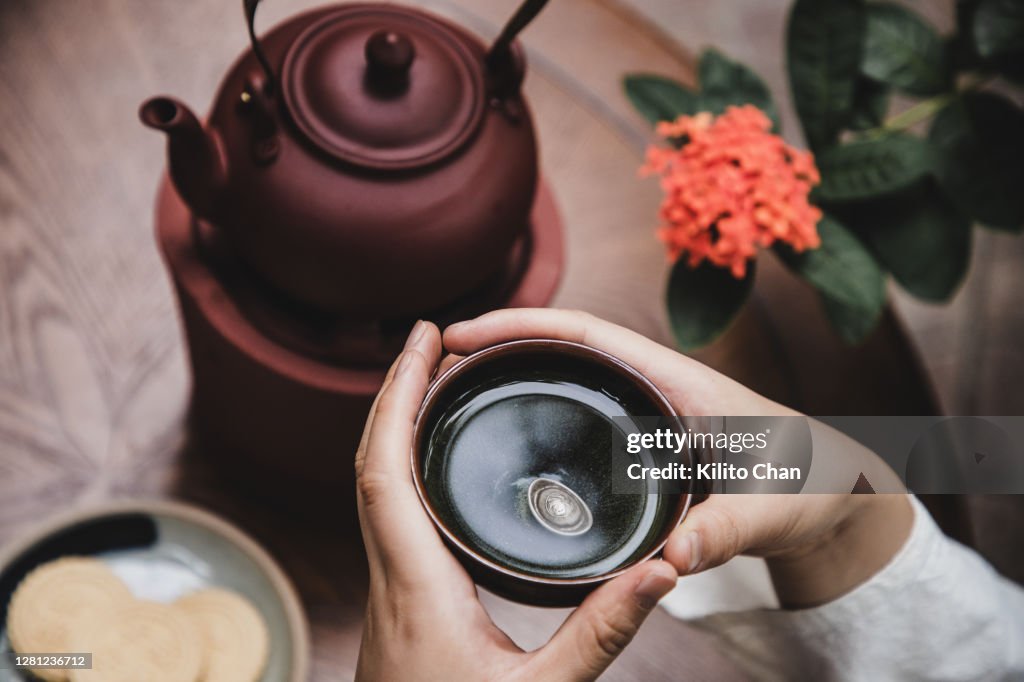 Asian woman enjoying hot green tea with snacks on the side