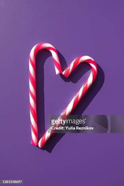 two candy sticks making heart shape form on the purple background - rock object stock pictures, royalty-free photos & images