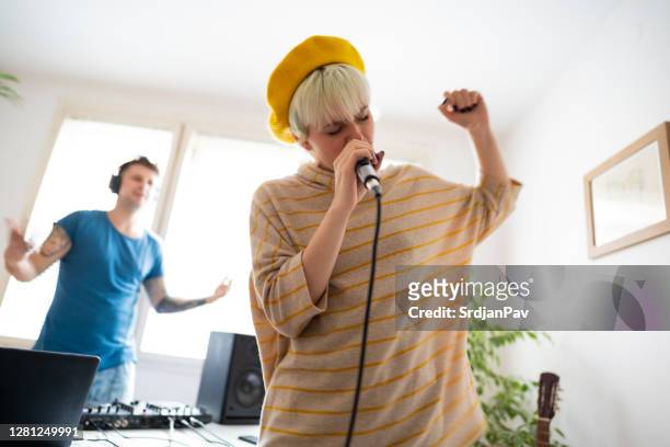 young female rapper rapping while the dj plays the music in home music studio - rapper stock pictures, royalty-free photos & images