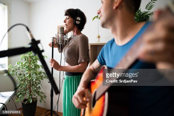 pareja joven disfrutando de la grabación de su nueva canción en el estudio de música - melody maker fotografías e imágenes de stock