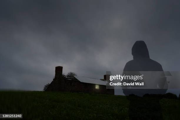 a transparent ghostly hooded figure. looking at a spooky ruined house with a light in the window on a stormy night - the house of spirits stock pictures, royalty-free photos & images