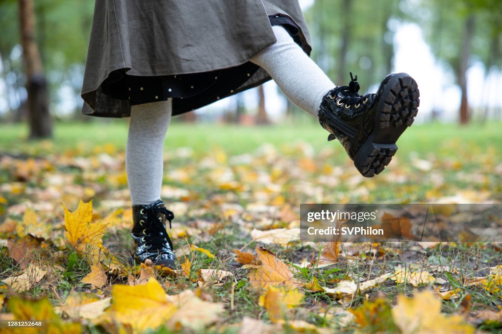 Child's feet while walking in the autumn park.