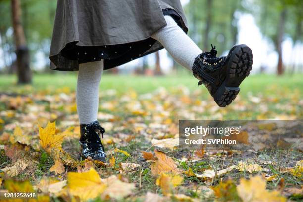 child's feet while walking in the autumn park. - boot stock pictures, royalty-free photos & images