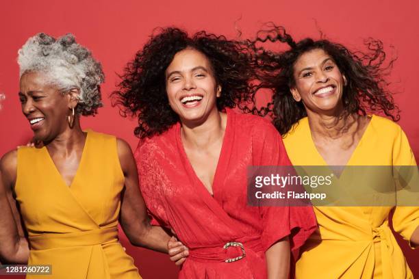 portrait of a group of mature women against a red background - nur frauen stock-fotos und bilder