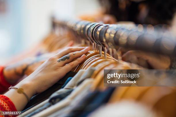 mujer mirando a través de la ropa - clothes rack fotografías e imágenes de stock