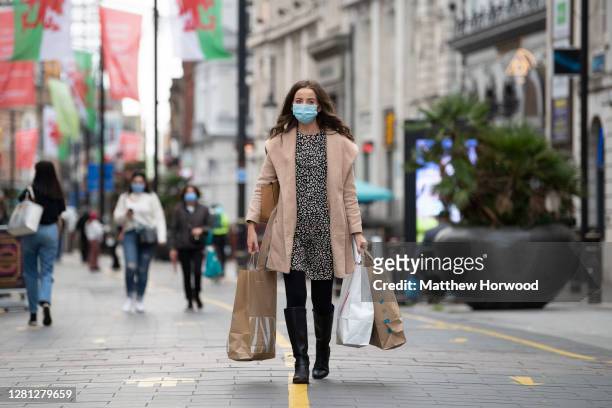 Woman wearing a surgical face mask carries bags of shopping on St. Mary Street on October 20, 2020 in Cardiff, Wales. Wales will go into a national...