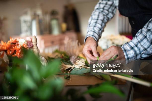 male florist adding finishing touches to flower arrangement at flower shop - close up of flower bouquet stock pictures, royalty-free photos & images