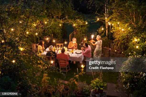 friends talking and dining outside on a warm summers evening. - outdoor dining stock pictures, royalty-free photos & images