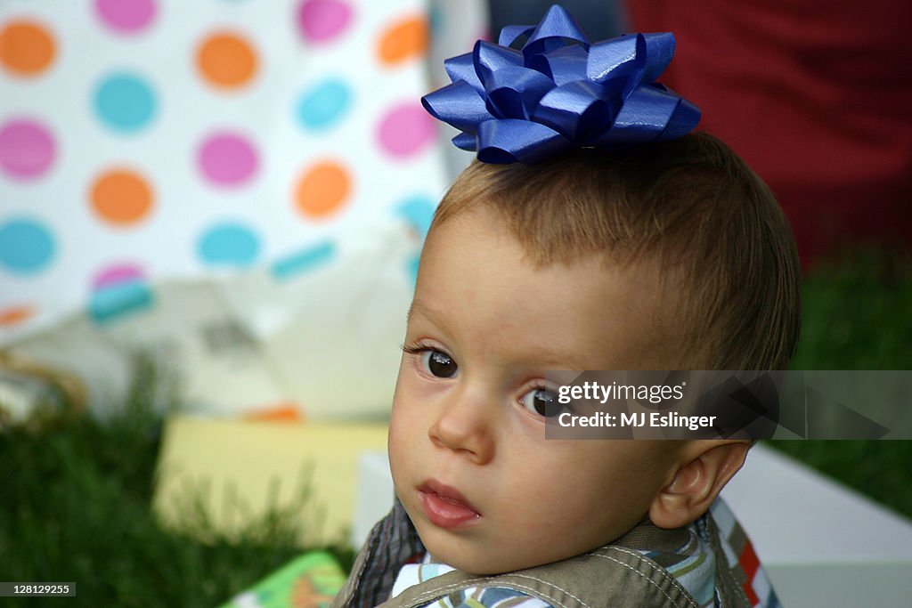 A baby boy with present bow on his head