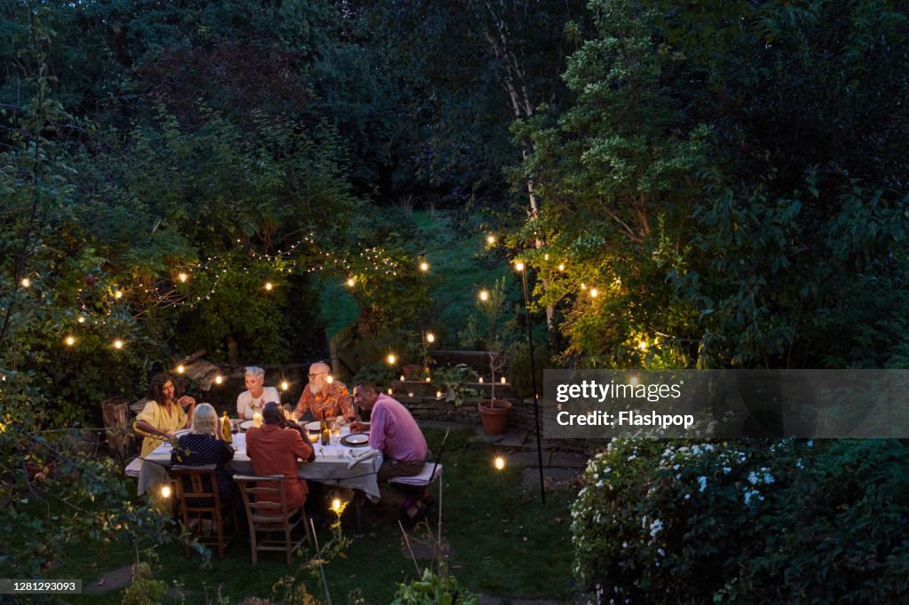 Friends talking and dining outside on a warm summers evening.