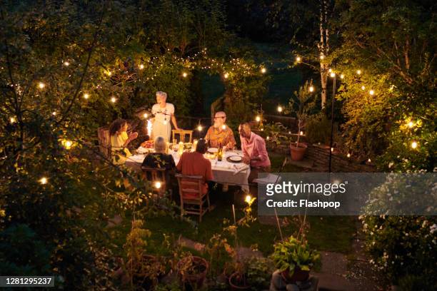 friends talking and dining outside on a warm summers evening. - garden lighting bildbanksfoton och bilder