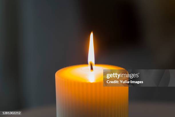 large cylindrical burning white candle - religious service stock-fotos und bilder