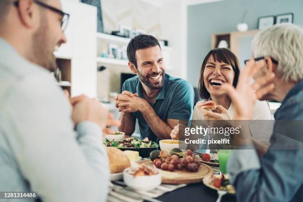 partager la nourriture et les bons rires - happy family eating photos et images de collection