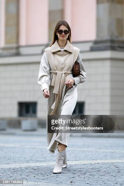 Influencer Jacqueline Zelwis, wearing a long beige dress by Black Palms the Label, a beige knitted vest by Holzweiler, beige boots with crocodile...