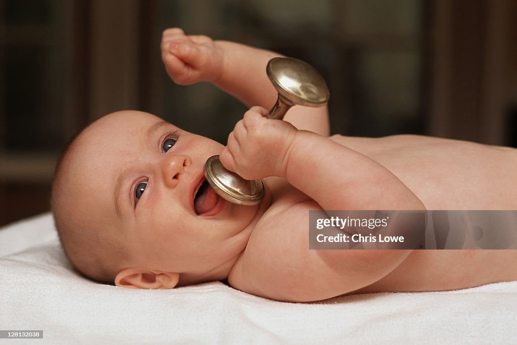 CHIPL004 Infant lying in crib holding rattle