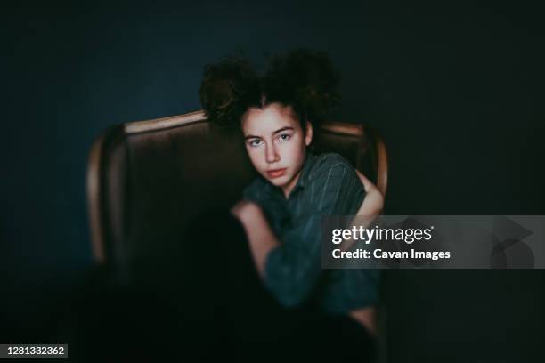 girl in green chair curled up - love photos et images de collection