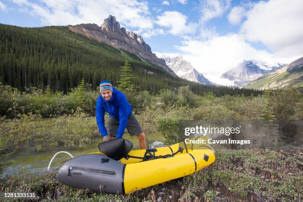 excited man inflates his packraft before paddling the alexandra river. - inflate stock-fotos und bilder