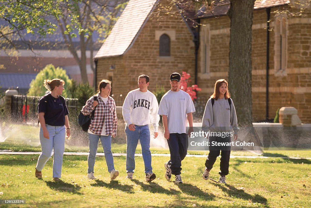 Students walking across lawn of college campus