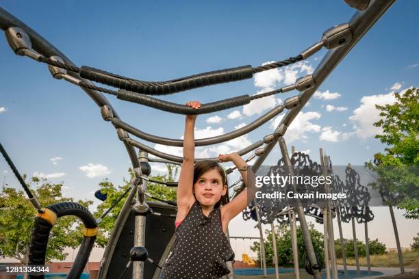 young girl concentrates as she plays on the monkey bars at playground - tag 7 bildbanksfoton och bilder