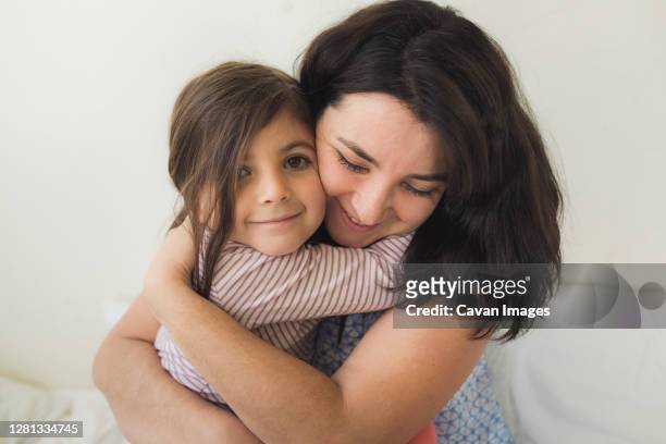 smiling mid-30's mother hugging happy 6 yr old daughter - s dear mama event stock pictures, royalty-free photos & images