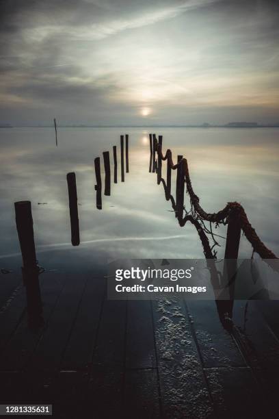 old wooden port submerged at sunrise - estuario stock pictures, royalty-free photos & images