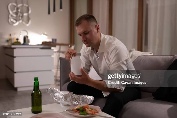 businessman eating delivery food at home - generation x stock pictures, royalty-free photos & images
