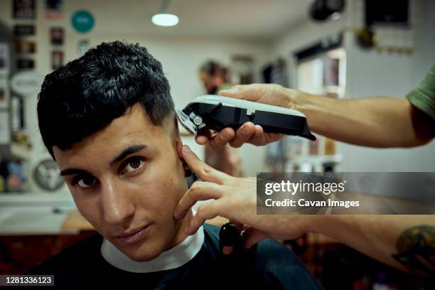 a young boy looking at the camera while having his hair cut by machine - jaén city stock pictures, royalty-free photos & images