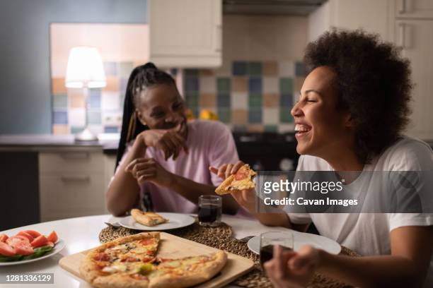 mixed race woman laughing at joke near friend - pizza party stock pictures, royalty-free photos & images