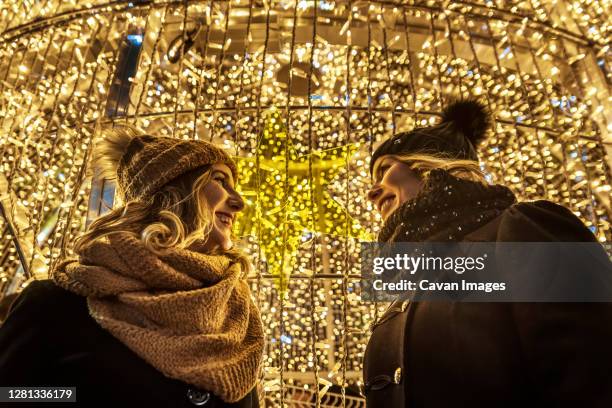 two young girls are laughing in the background of christmas lights - madrid christmas stock pictures, royalty-free photos & images