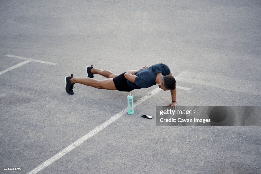 A young boy is doing push up exercises in the street