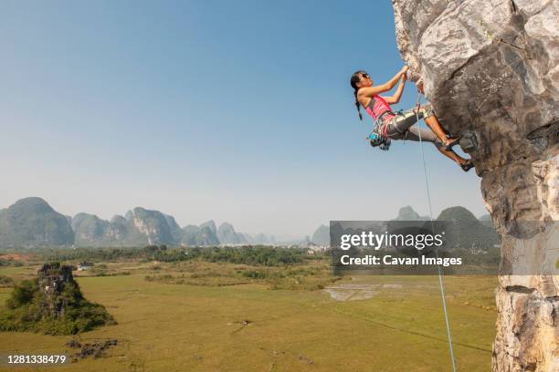 female climber pulling up on overhanging rock in yangshuo / china - rock overhang foto e immagini stock