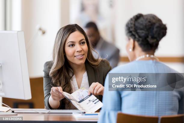 bank employee explains bank services to new customer - pamphlet stock pictures, royalty-free photos & images