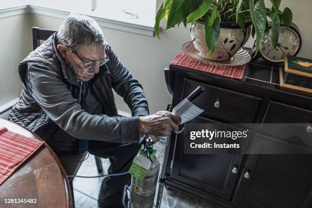 in order to make sure the settings are correct, a senior man is checking his portable oxygen tank before having breakfast. - oxygen cylinder stock pictures, royalty-free photos & images