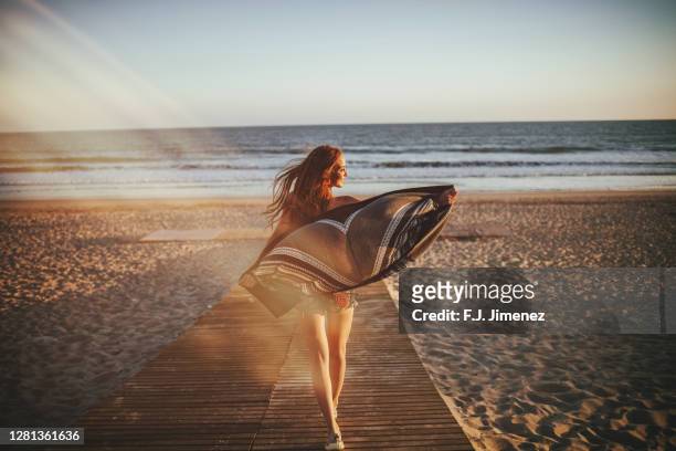 back view of girl walking on beach - girl blowing sand stock-fotos und bilder