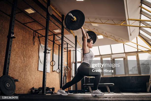 geschikte vrouwenopleiding met gewichten in gymnastiek - gewichtheffen sport stockfoto's en -beelden