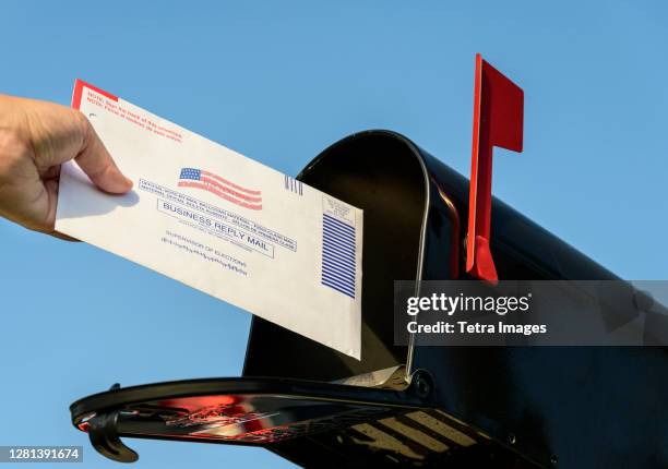 woman's hand placing a 2020 mail-in election ballot in a rural mailbox - voting ballot stockfoto's en -beelden