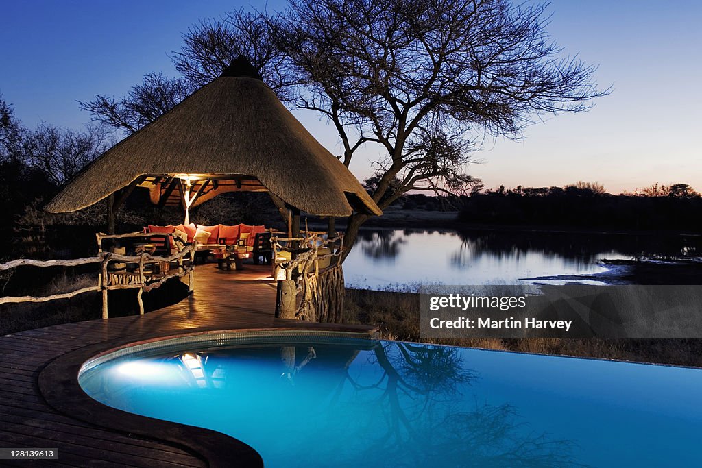 Night shot of the beautifully decorated lapa and swimming pool area at the Villa in Okonjima Private Game Reserve, Namibia. This luxury lodge offers guest the opportunity to view game drinking at the waterhole. (PR: Property Released)