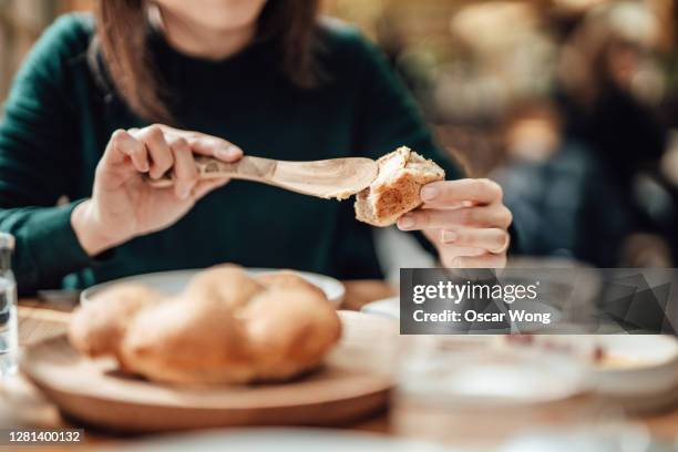 young woman buttering bread at the restaurant - pan fotografías e imágenes de stock