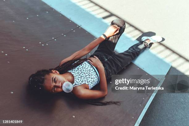 portrait of a  girl with an inflated gum on a skateboard. - girl in black jeans stockfoto's en -beelden