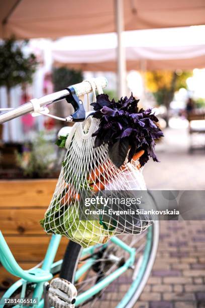 bicycle with a bag of mixed vegetables and greenery. - shopping with bike stock-fotos und bilder