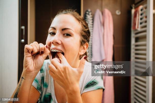 用牙線清潔牙齒的女人。 - brace 個照片及圖片檔