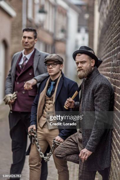 group of armed gangster men in an old city alleyway - gangster stock pictures, royalty-free photos & images